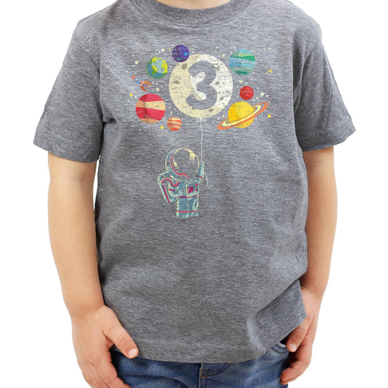 Flat lay of black kids birthday tee with astronaut rocket and moon balloon graphic