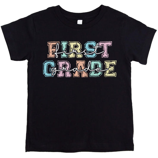 First grade shirt for girls laid flat showing full colorful pastel letter graphic print