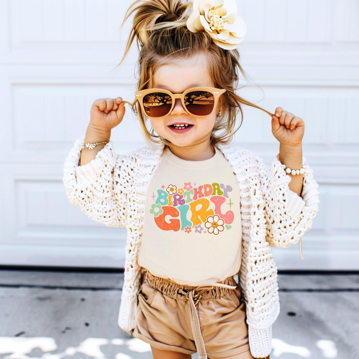 Toddler wearing birthday girl groovy flowers shirt as part of birthday outfit