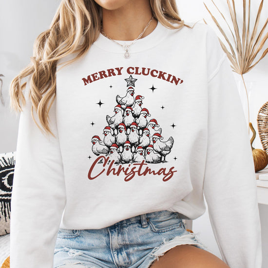 Close-up of Merry Cluckin' Christmas holiday graphic with chickens in Santa hats on white sweatshirt