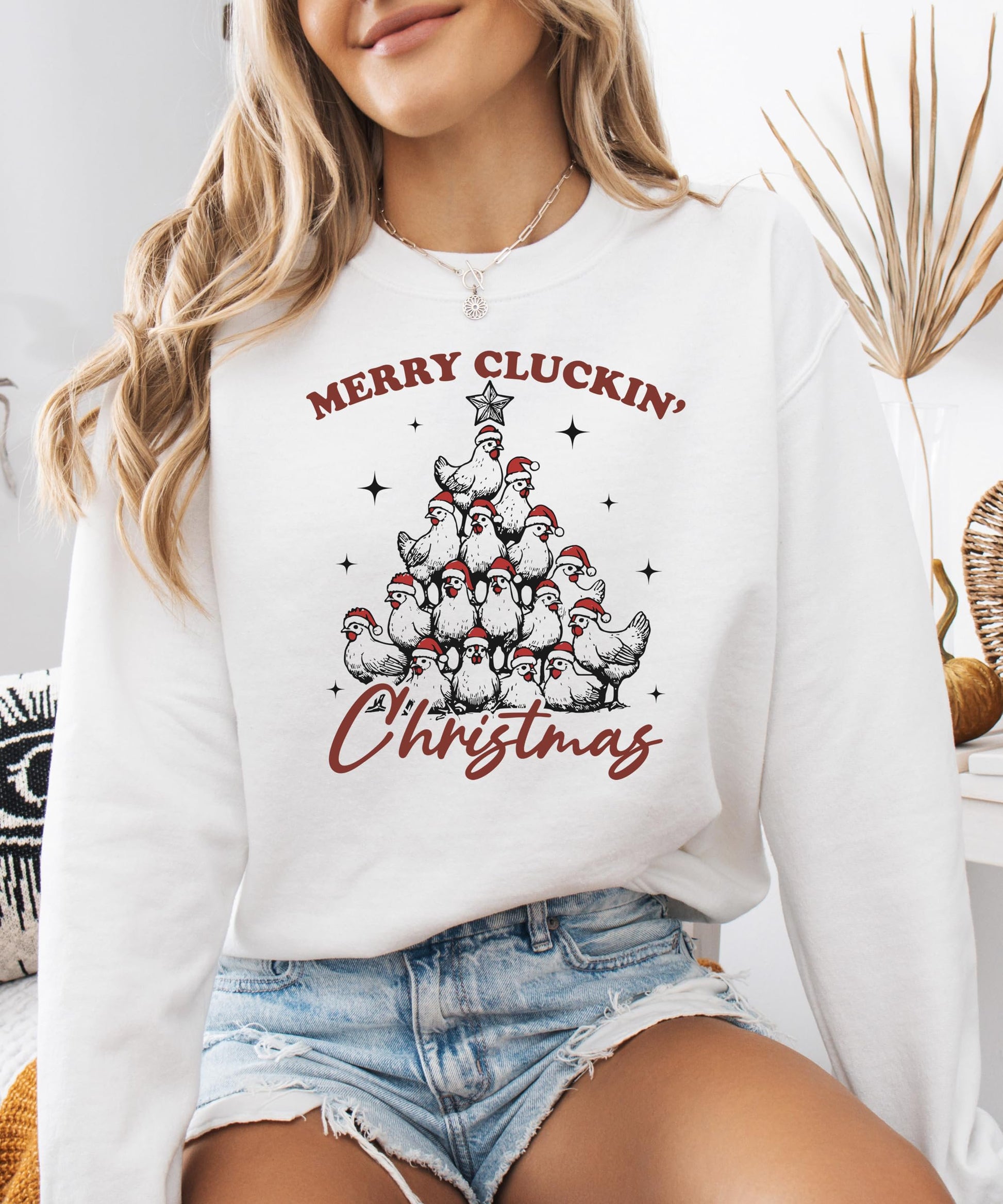 Close-up of Merry Cluckin' Christmas holiday graphic with chickens in Santa hats on white sweatshirt