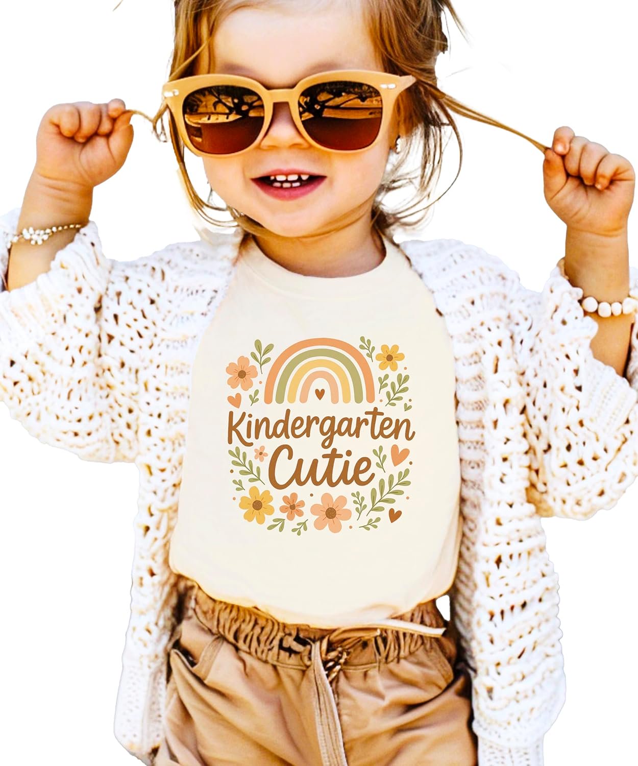 Flat lay of Kindergarten Cutie girls' natural tee showing full rainbow and daisy print detail