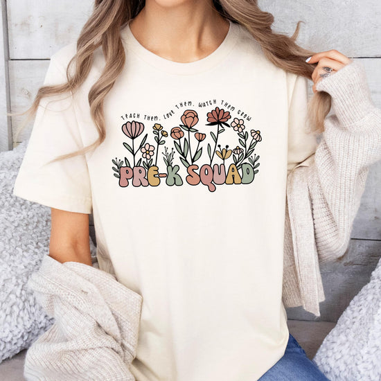 Flat lay of Pre-K Squad floral teacher shirt showing full design and peach color
