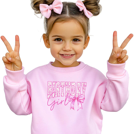 White pullover sweatshirt with bold pink Birthday Girl text and pink bow graphic for women and girls