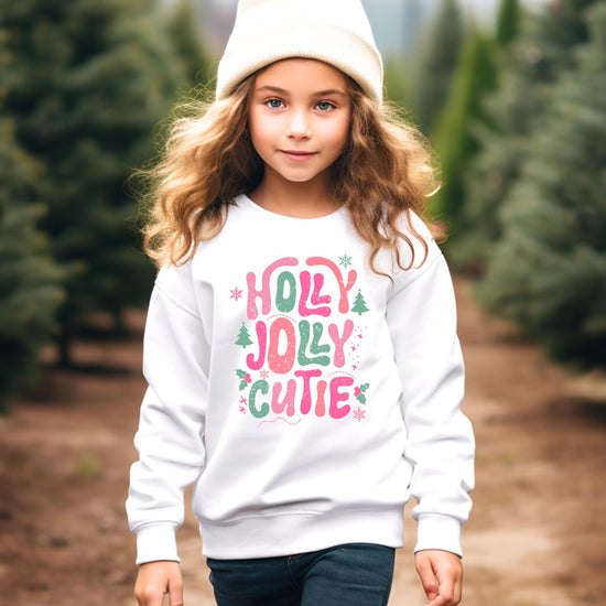 Flat lay of black girls Christmas sweatshirt featuring Holly Jolly Cutie holiday graphic