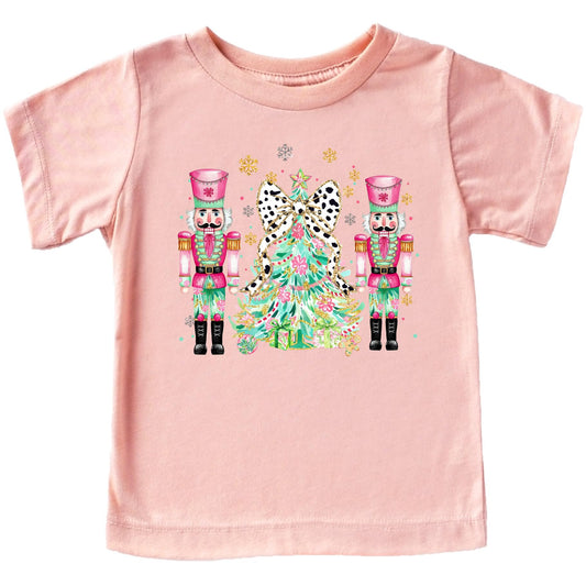 Women's peach t-shirt featuring a colorful nutcracker and Christmas tree holiday graphic design