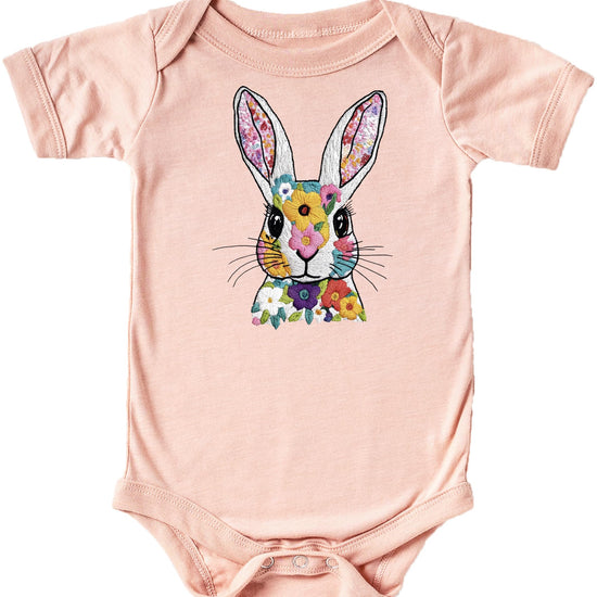 Close-up of floral rabbit ink print on a soft peach baby onesie