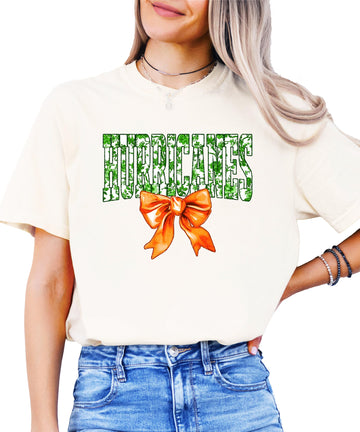 Close-up of green floral 'Hurricanes' graphic with vibrant orange bow on a women's ivory tee