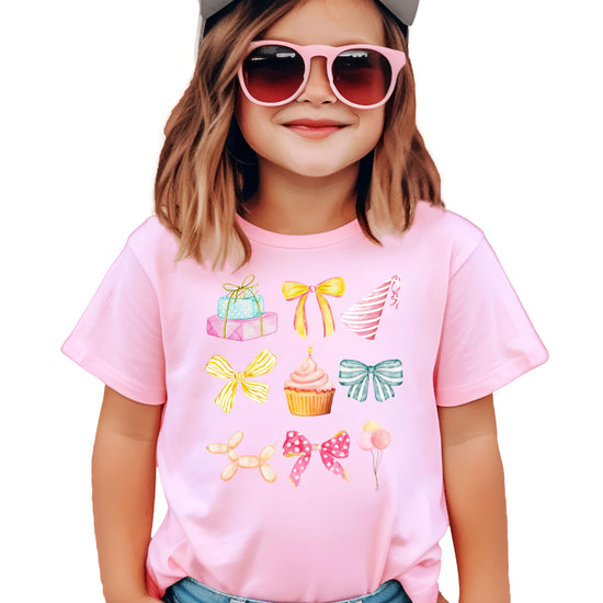 Close-up of coquette birthday shirt print showing soft watercolor cupcakes, party hats, presents, and balloons