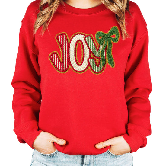Model wearing cozy JOY Christmas sweatshirt in festive holiday colors