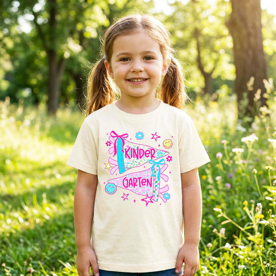 Kindergarten shirt for girls laid flat on natural background showing full pennant graphic and soft cotton fabric