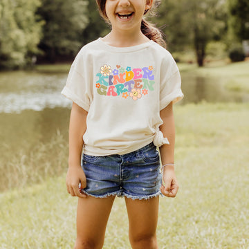 Youth girl wearing natural groovy daisy first day of school kindergarten graphic tee, styled flat lay
