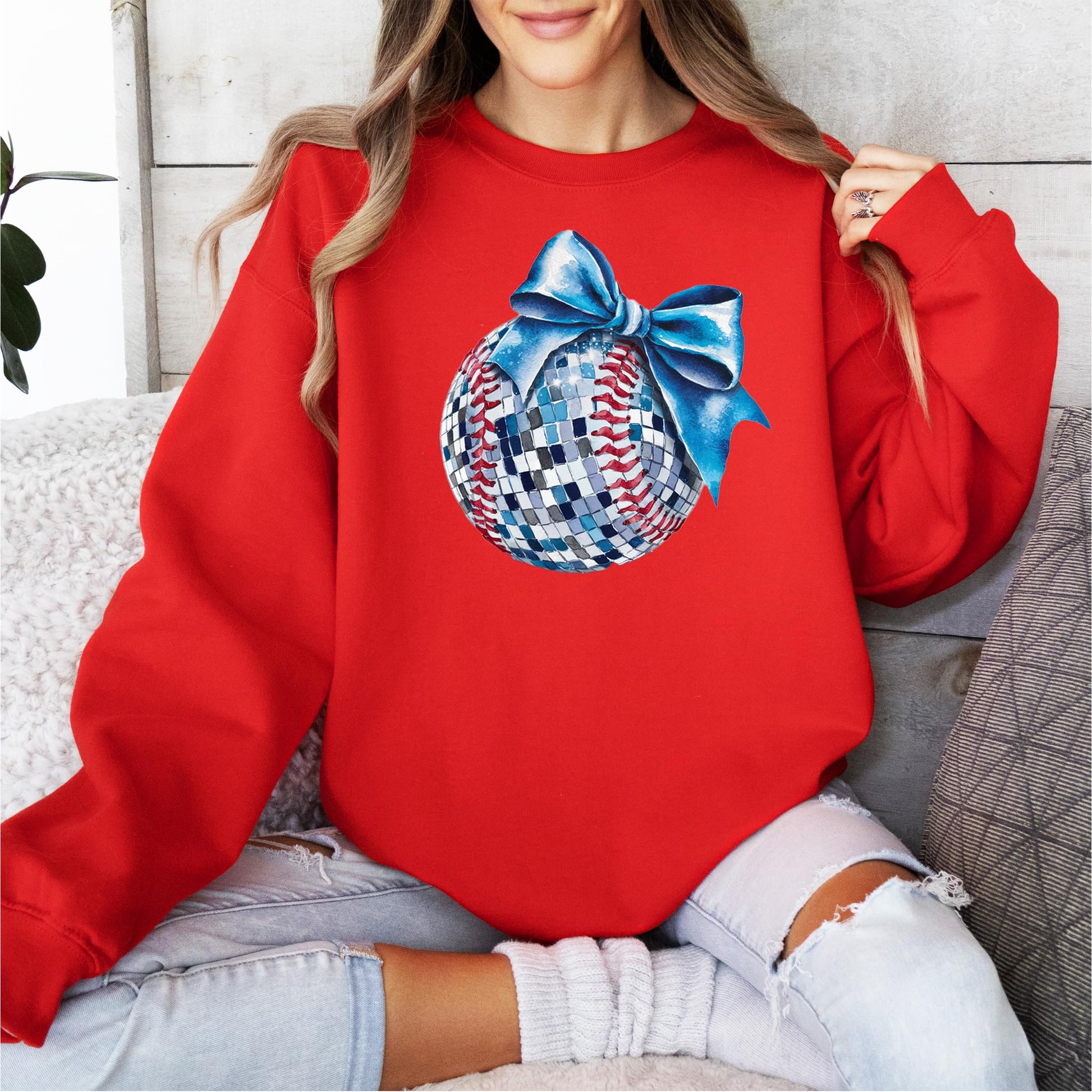 Woman wearing gray disco softball sweatshirt with blue bow graphic