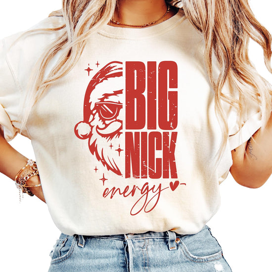 Women's ivory Big Nick Energy Christmas t-shirt with cool Santa wearing sunglasses graphic