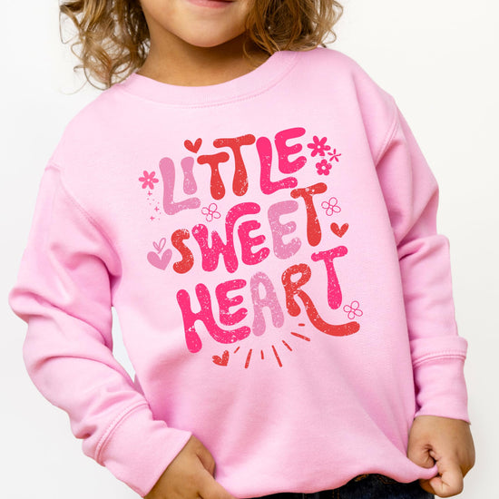 Front view of Little Sweet Heart pink sweatshirt for girls on a flat lay background