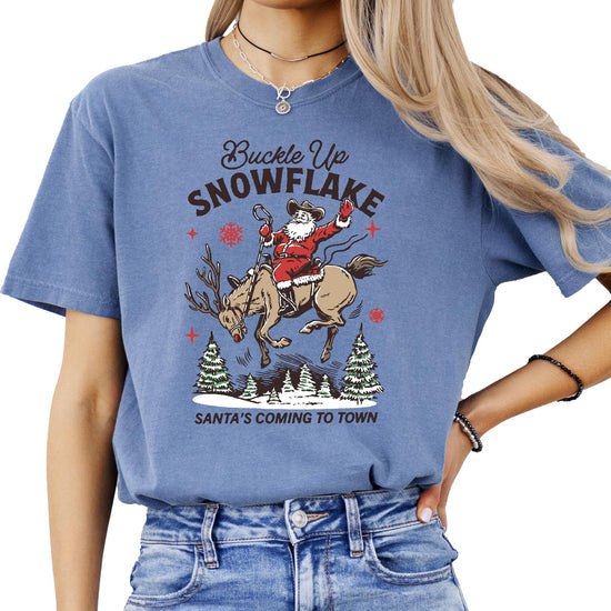 Flat lay of ivory Buckle Up Snowflake Santa's Coming to Town Christmas graphic tee