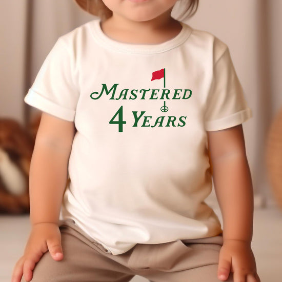 Boy or girl wearing Mastered 4 Years golf themed 4th birthday t-shirt in natural color