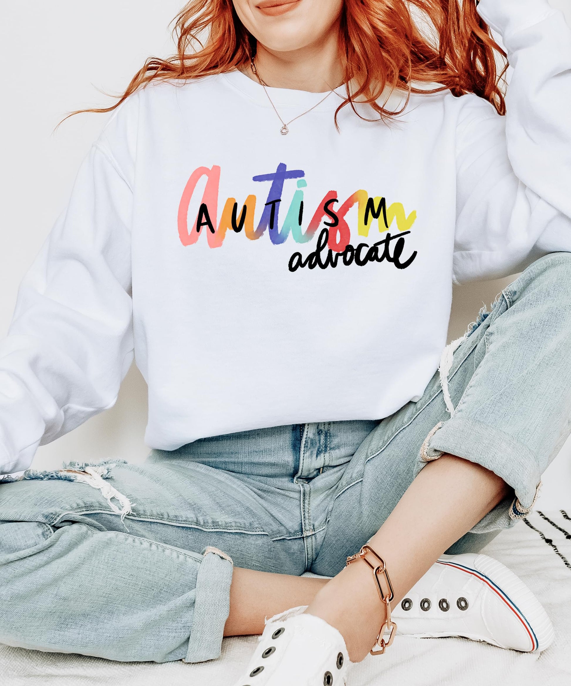 Detail shot of soft white pullover sweatshirt with bold autism awareness graphic by Olive Loves Apple