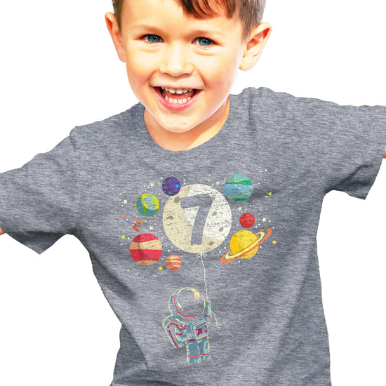 Flat lay of kids space birthday shirt showing full rocket astronaut and planets graphic