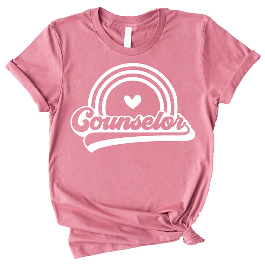 Close-up of retro rainbow counselor shirt print, vibrant colorful graphic on peach tee