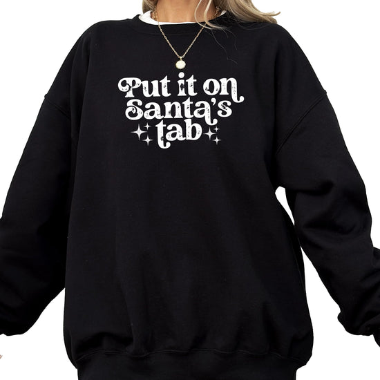 Front view of red holiday graphic sweatshirt with 'Put It on Santa's Tab' humorous Christmas design