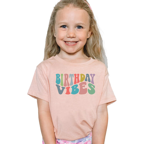 Flat lay of Birthday Vibes youth girls birthday tee in peach colorway