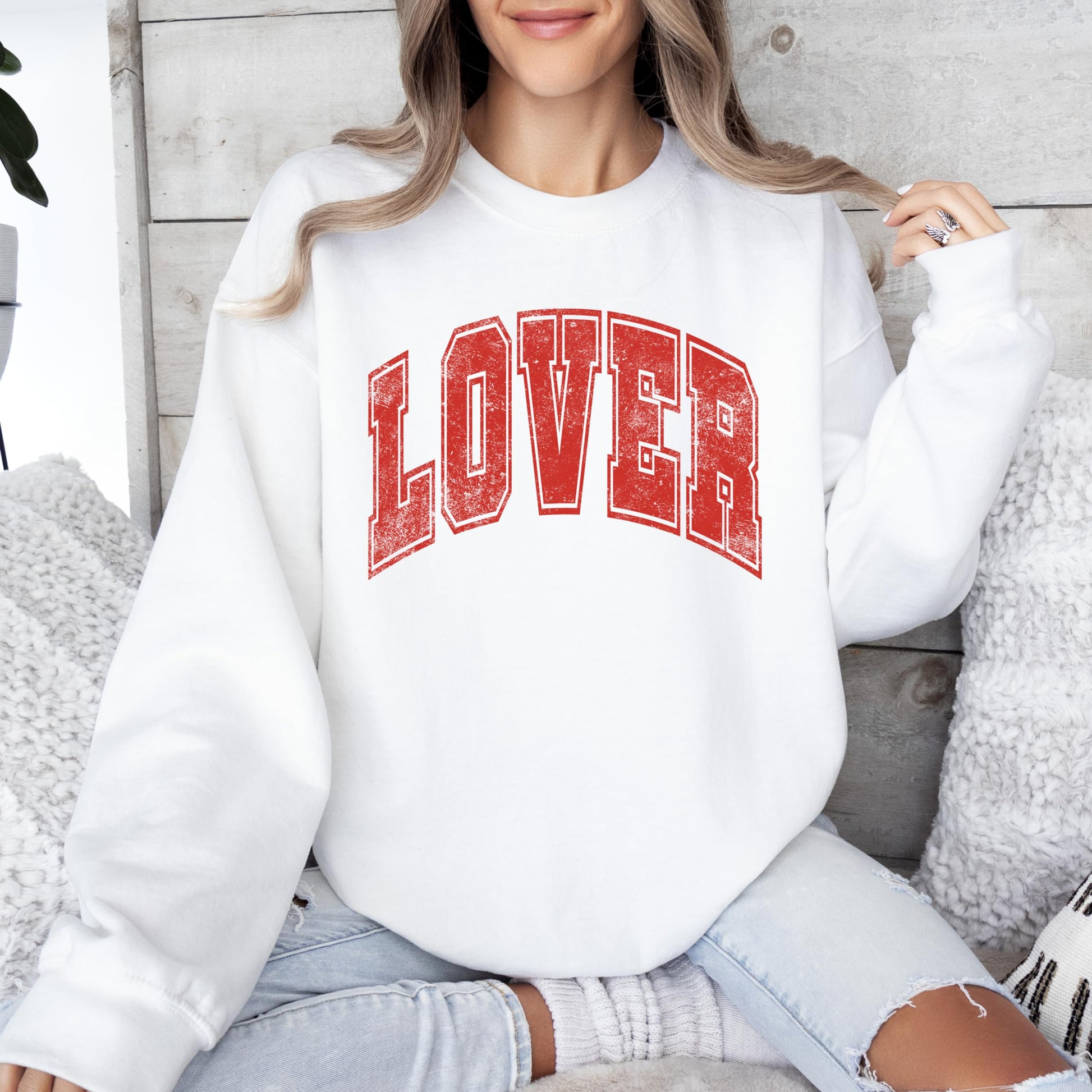 Close-up of distressed red varsity Lover graphic print on white sweatshirt