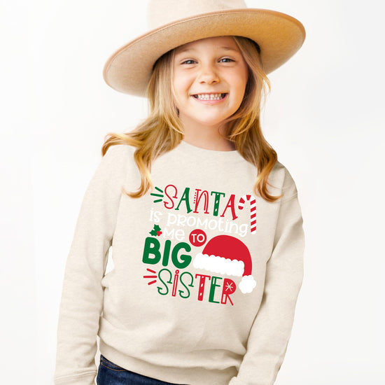 Full-length view of toddler wearing a holiday Big Sister announcement sweatshirt with Santa design