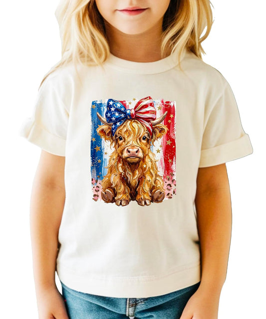 Pink patriotic Highland cow graphic tee with stars-and-stripes bow and watercolor American flag design for women and girls