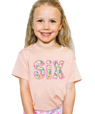 Peach kids tee with floral SIX design and pink embroidered-look print for girls 6th birthday