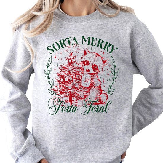 Flat lay of white funny holiday crewneck sweatshirt with Sorta Merry Sorta Feral raccoon design