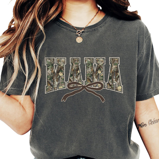 Detail shot of coquette bow and camo varsity letter print on seafoam women's graphic tee