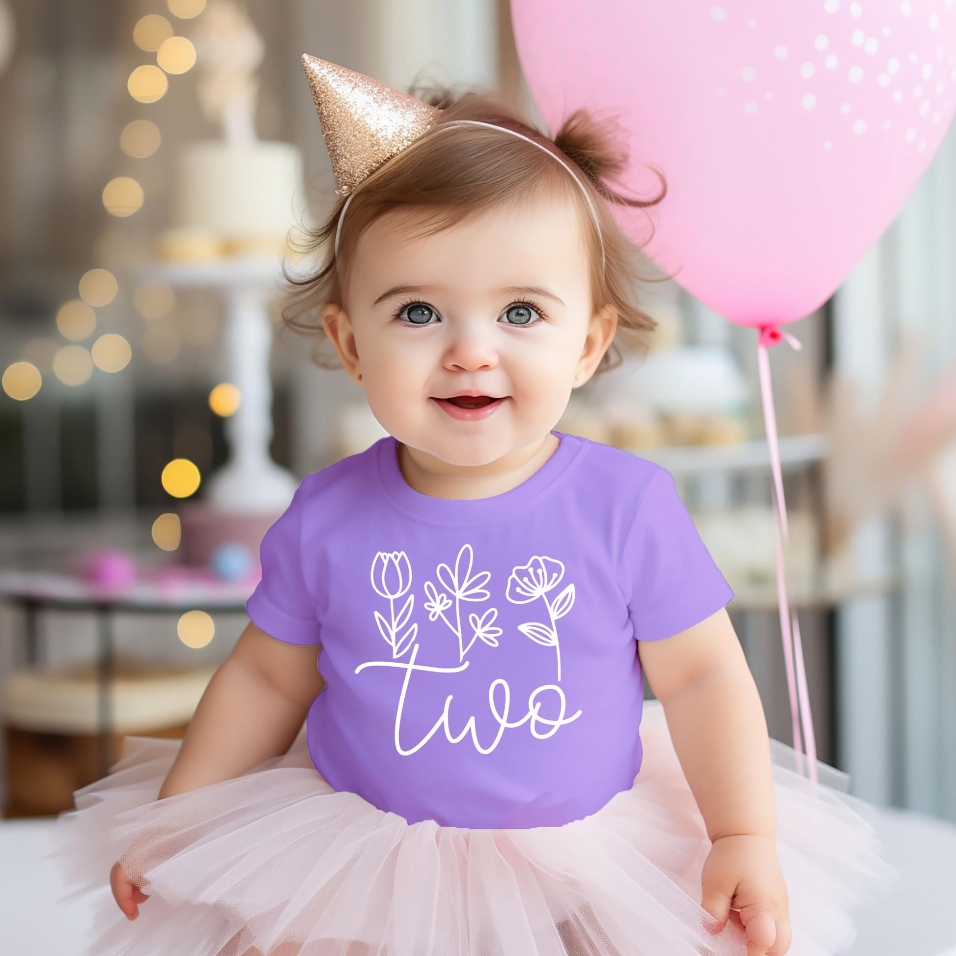Side view of toddler modeling mauve Two floral birthday shirt with cursive lettering