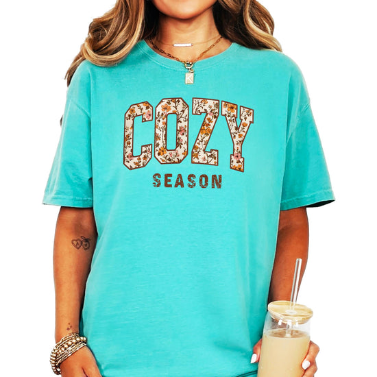 Close-up of orange floral print Cozy Season design on ivory women's t-shirt
