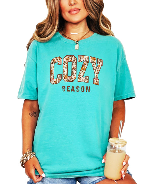 Close-up of orange floral print Cozy Season design on ivory women's t-shirt