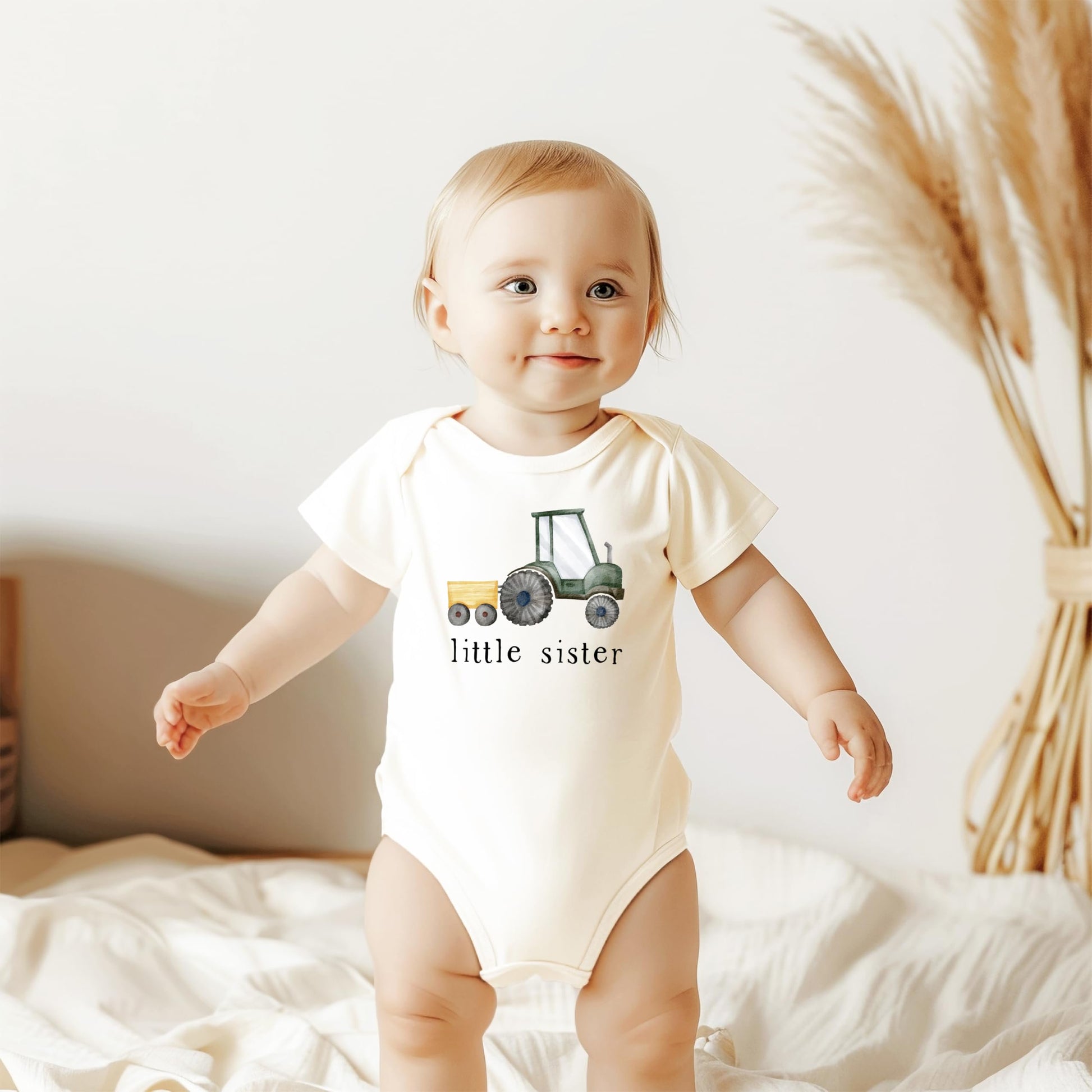 Little sister tractor bodysuit displayed as sibling reveal family outfit for new baby girl