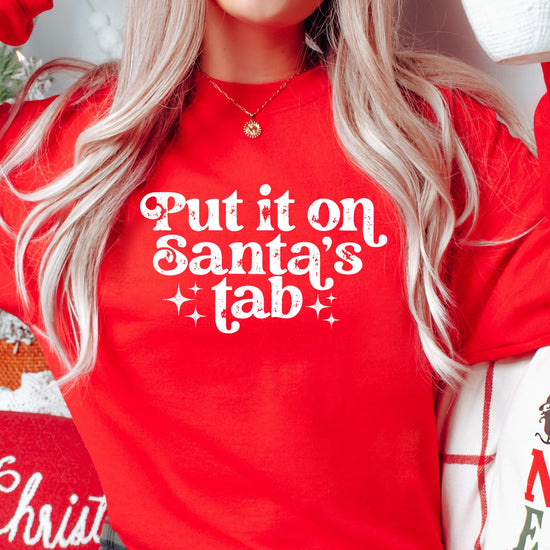 Flat lay of red 'Put It on Santa's Tab' funny Christmas sweatshirt for women and teens