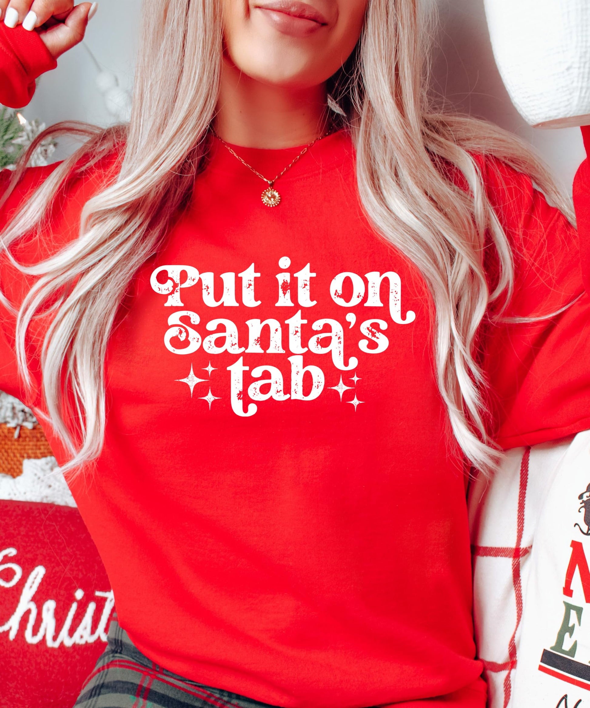 Flat lay of red 'Put It on Santa's Tab' funny Christmas sweatshirt for women and teens