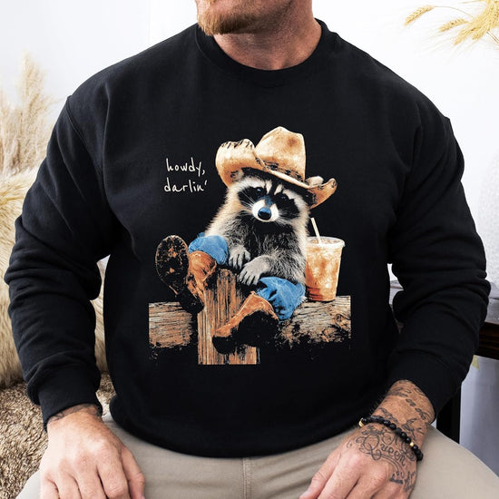 Close-up of cowboy raccoon 'Howdy' graphic print on black fleece sweatshirt