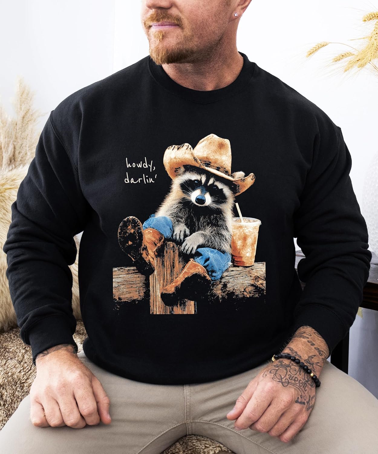Close-up of cowboy raccoon 'Howdy' graphic print on black fleece sweatshirt