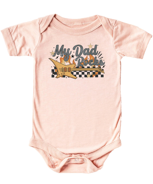Flat lay of peach My Dad Rocks baby one-piece bodysuit with retro guitar art