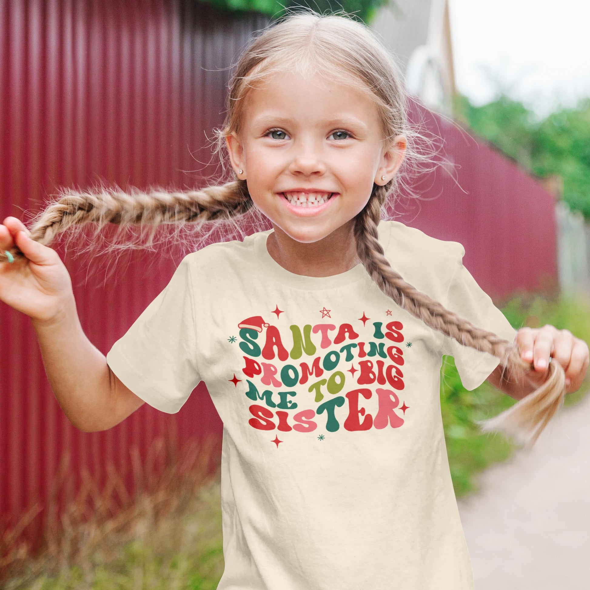 Flat lay of beige big sister Christmas shirt showing full groovy text design