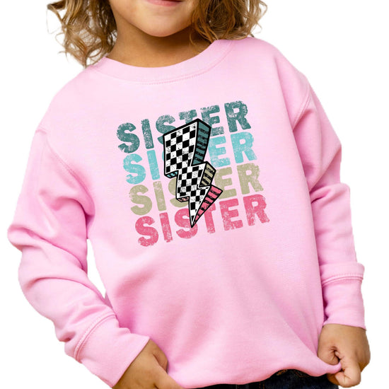 Girls pink pullover sweatshirt with bold colorful SISTER lettering and retro checkered lightning bolt graphic