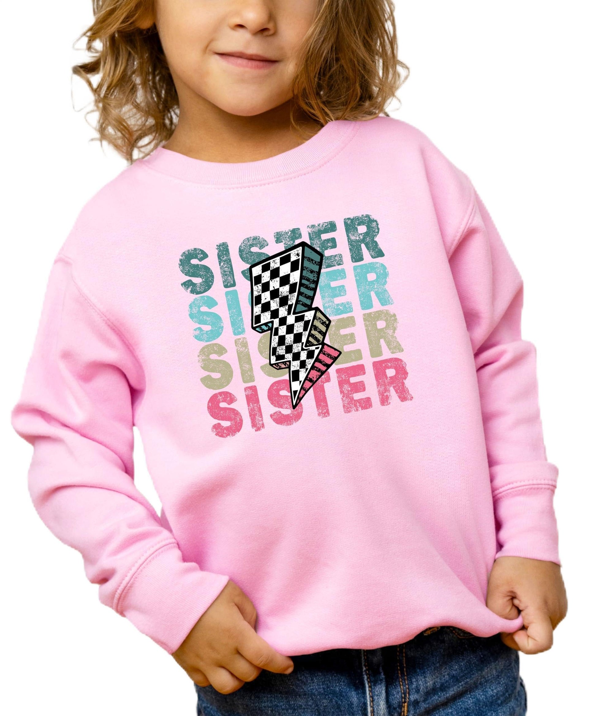 Girls pink pullover sweatshirt with bold colorful SISTER lettering and retro checkered lightning bolt graphic
