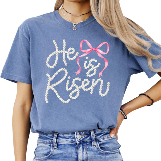 Detail shot of pearl-style He Is Risen graphic with pink bow on soft women's Easter tee