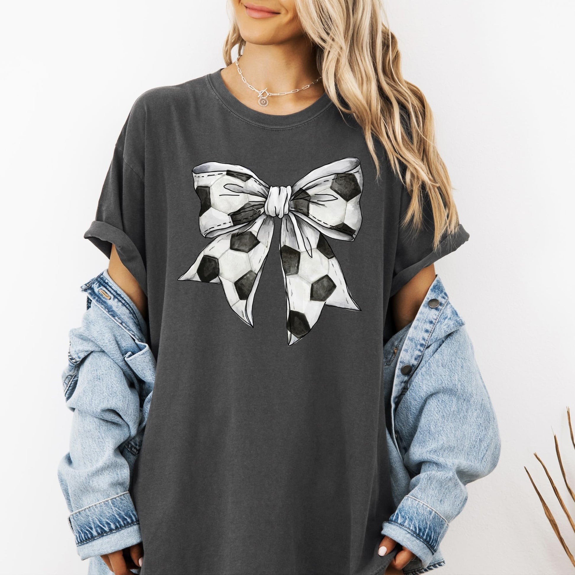 Flat lay of seafoam coquette bow soccer tee showing full graphic design