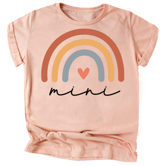 Flat lay of mommy and me matching rainbow heart peach graphic tee and infant bodysuit set