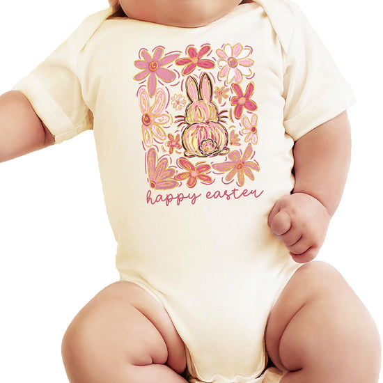 Flat lay of boho Easter baby bodysuit with flowers and bunny graphic on natural fabric