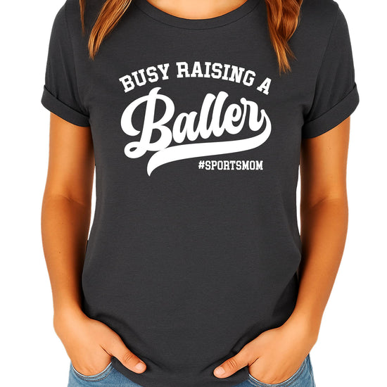 Busy Raising a Baller women's black graphic tee, lifestyle flat lay