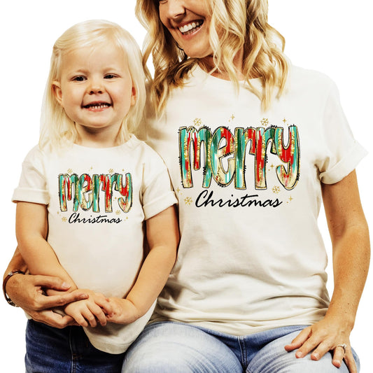 Flat lay of peach Merry Christmas watercolor matching tee for women and girls